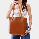 Sienna Medium Classic | Model holding a leather tote bag with riveted straps and exterior key loop