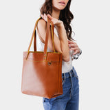 Sienna Medium Classic | Model holding a leather tote bag with riveted straps and exterior key loop