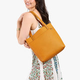 Sunshine Medium Classic| Model wearing leather tote bag with riveted straps and exterior key loop
