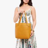 Sunshine Medium Classic| Model wearing leather tote bag with riveted straps and exterior key loop