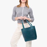 Westward Blue Medium Classic | Model wearing leather tote bag with riveted straps and exterior key loop