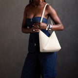 Pebbled Bone Small | Model carrying petite shoulder bag with adjustable strap and magnetic snap closure