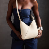 Pebbled Bone Small | Model holding petite shoulder bag with adjustable strap and magnetic snap closure