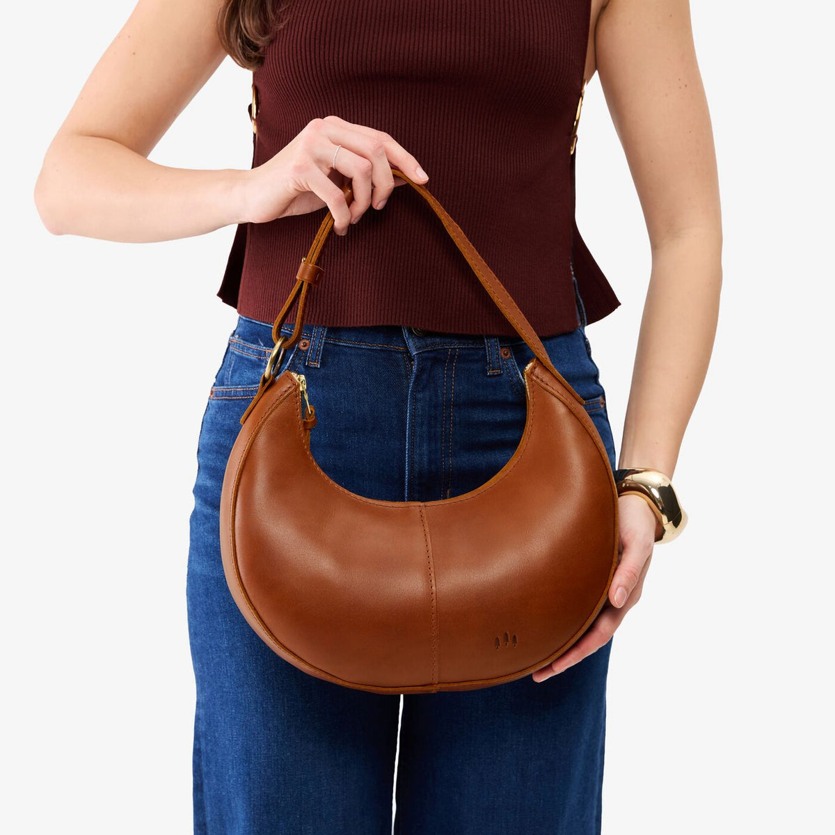 Honey*Small | Model holding crescent shaped leather shoulder bag with zipper closure and adjustable strap