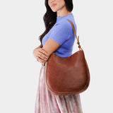 Nutmeg Large | Woman wearing rounded shoulder bag with adjustable strap on a white background