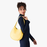 Butter Bliss Medium | Model carrying round leather purse with adjustable shoulder strap