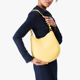 Butter Bliss Medium | Model carrying round leather purse with adjustable shoulder strap