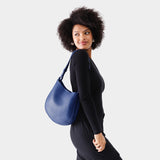 Molino Blue Medium | Woman wearing rounded shoulder bag with adjustable strap on a white background