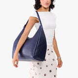 Cobalt Oversized | Model carrying U-shaped, flat-bottomed leather shoulder bag with adjustable strap