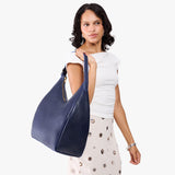 Cobalt Oversized | Model carrying U-shaped, flat-bottomed leather shoulder bag with adjustable strap