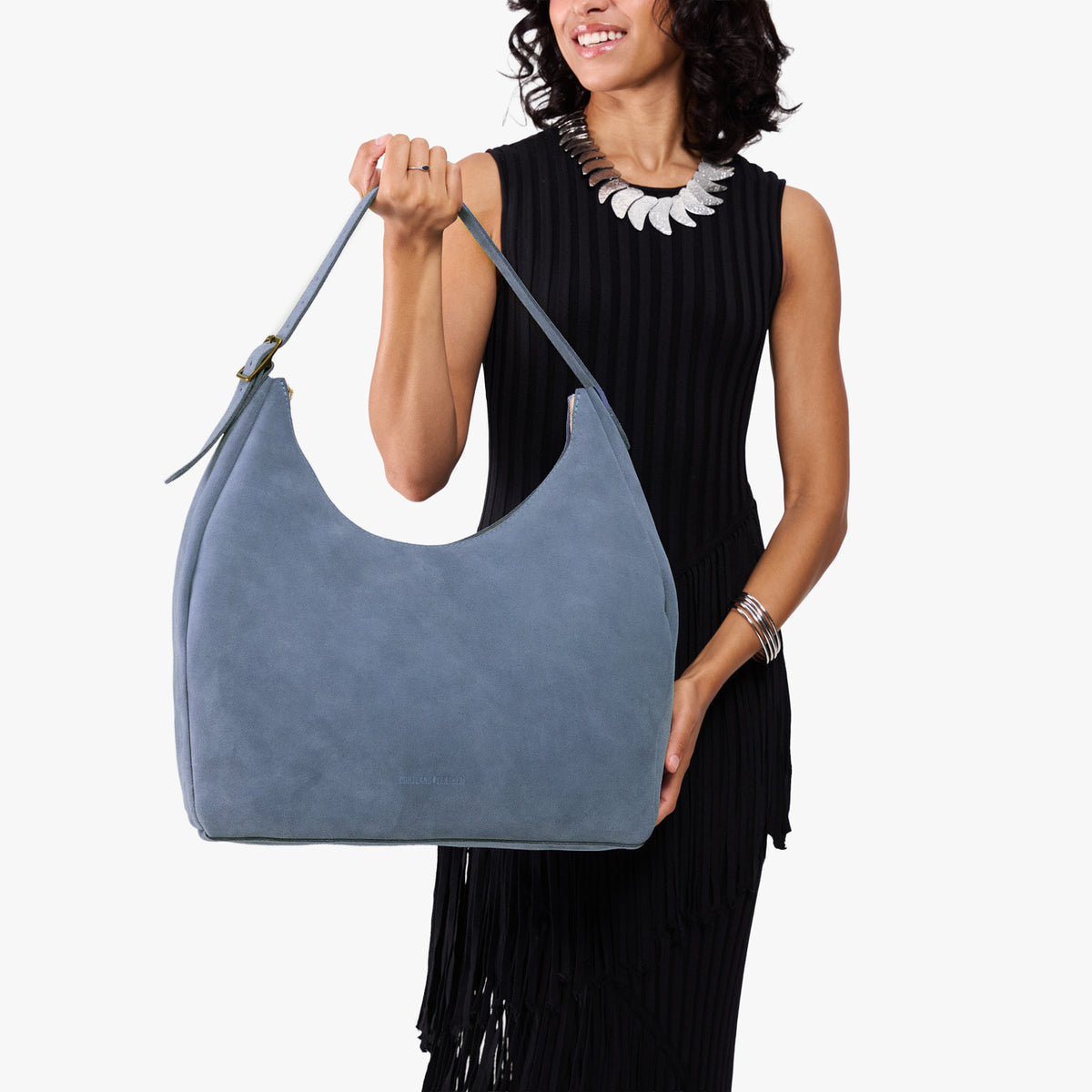 Denim*Oversized | Model holding u-shaped, flat-bottomed leather shoulder bag with adjustable strap