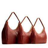 Nutmeg | Size comparison image of oversized, large, and medium u-shaped, flat-bottomed leather shoulder bags with adjustable strap