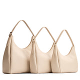 Pebbled Bone | Size comparison image of oversized, large, and medium u-shaped, flat-bottomed leather shoulder bags with adjustable strap
