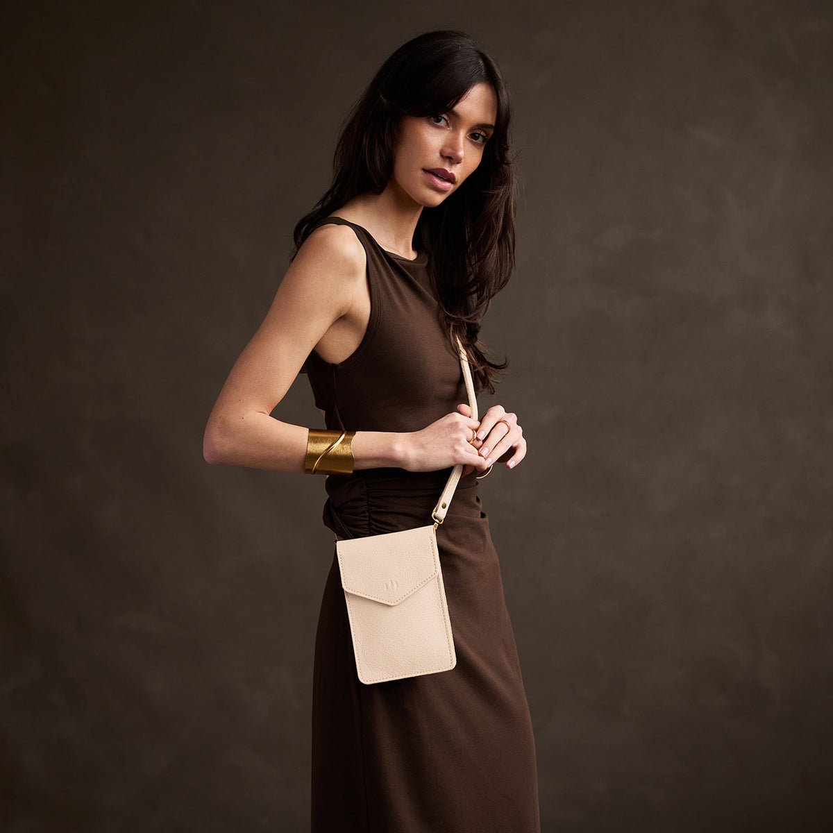 Pebbled Bone | Model wearing slim, phone-shaped crossbody purse with magnetic closure