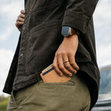 Naturale | A close up of a model sliding a leather card holder into their back pants pocket