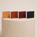 Nero | Group of wallets  lined up on top of a textured beige stone cylinder