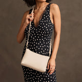 Pebbled Bone Small | Model wearing a zip top petite crossbody bag with detachable strap