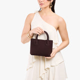 Velvet Brown Small | Model holding petite tote purse with structured leather handles and crossbody strap