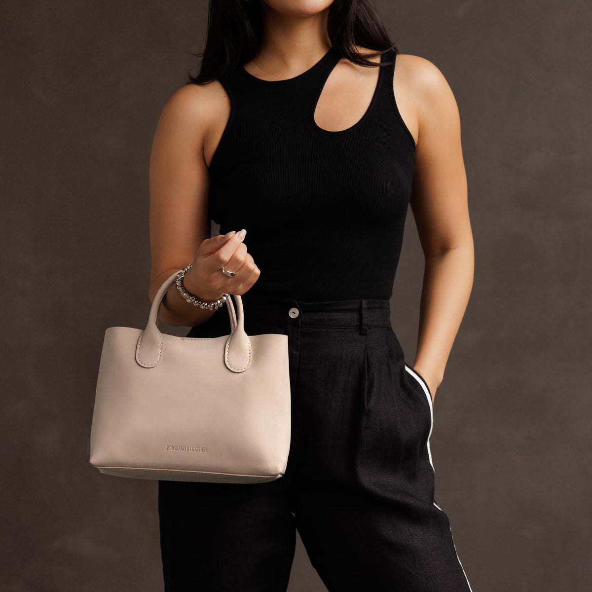 Dragon Bone*Large | Model holding mid-size tote purse with  structured leather handles and crossbody strap