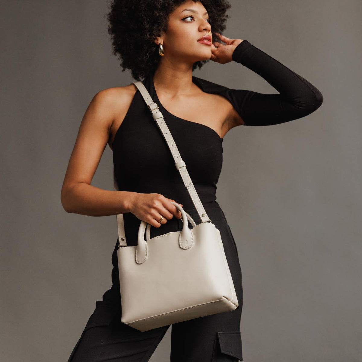 Bone*Large | Model holding mid-size tote purse with  structured leather handles and crossbody strap