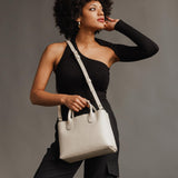 Bone Large | Model holding mid-size tote purse with  structured leather handles and crossbody strap