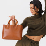 Honey Large | Model holding mid-size tote purse with  structured leather handles and crossbody strap