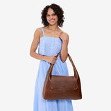 Asheville Large | A model holding a slouchy triangle shaped shoulder bag with a flap
