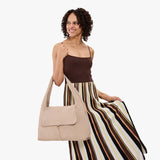 Taupe Large | A model holding a slouchy triangle shaped shoulder bag with a flap