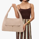 Taupe Large | A model holding a slouchy triangle shaped shoulder bag with a flap
