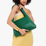 Bacalar Medium | A model holding a slouchy triangle shaped shoulder bag with a flap