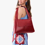 Chili Red Medium | A model holding a slouchy triangle shaped shoulder bag with a flap