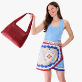 Chili Red Medium | A model holding a slouchy triangle shaped shoulder bag with a flap