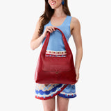 Chili Red Medium | A model holding a slouchy triangle shaped shoulder bag with a flap