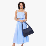 Cobalt Medium | A model holding a slouchy triangle shaped shoulder bag with a flap