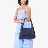 Cobalt Medium | A model holding a slouchy triangle shaped shoulder bag with a flap