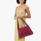 Orchid Medium | A model holding a slouchy triangle shaped shoulder bag with a flap