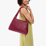 Orchid Medium | A model holding a slouchy triangle shaped shoulder bag with a flap