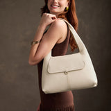 Pebbled Bone Medium | A model holding a slouchy triangle shaped shoulder bag with a flap
