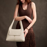 Pebbled Bone Medium | A model holding a slouchy triangle shaped shoulder bag with a flap