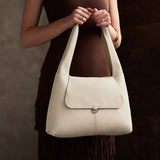 Pebbled Bone Medium | A model holding a slouchy triangle shaped shoulder bag with a flap