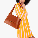 Sienna Medium | A model holding a slouchy triangle shaped shoulder bag with a flap