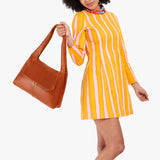 Sienna Medium | A model holding a slouchy triangle shaped shoulder bag with a flap