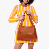Sienna Medium | A model holding a slouchy triangle shaped shoulder bag with a flap