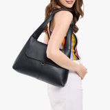Pebbled--black Medium | A model holding a slouchy triangle shaped shoulder bag with a flap