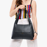 Pebbled--black Medium | A model holding a slouchy triangle shaped shoulder bag with a flap