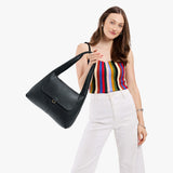 Pebbled--black Medium | A model holding a slouchy triangle shaped shoulder bag with a flap
