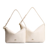 Pebbled Bone | Size comparison shot of small and large slouchy leather shoulder bags with zipper opening and three metal tree emblems
