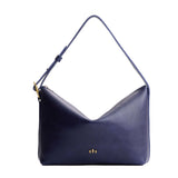 Cobalt Large | Model Wearing medium sized slouchy leather shoulder bag with zipper opening and three metal tree emblems