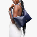 Cobalt Large | Model Wearing medium sized slouchy leather shoulder bag with zipper opening and three metal tree emblems