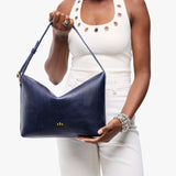 Cobalt Large | Model Wearing medium sized slouchy leather shoulder bag with zipper opening and three metal tree emblems